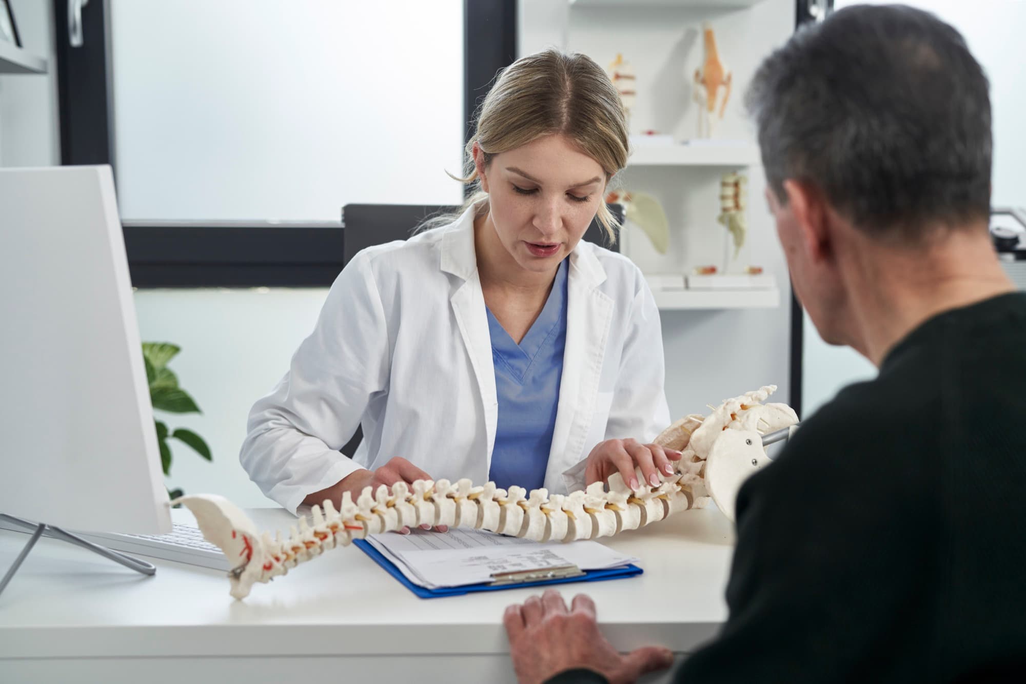 Clinician using a spine model to explain treatment to a patient in an MSK clinic