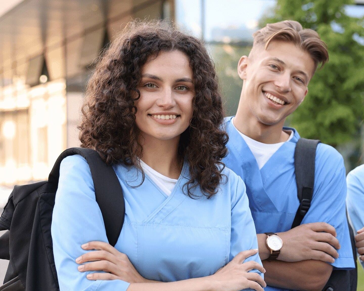 Two clinical students in scrubs outside a university building